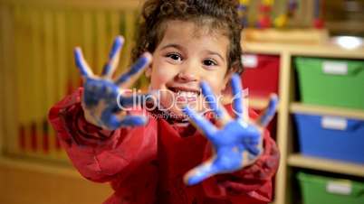 Happy children having fun and painting with hands in kindergarten