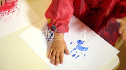 Little girls having fun and painting with hands at school