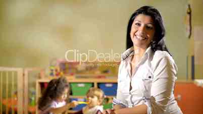 Portrait of happy teacher with children eating in kindergarten