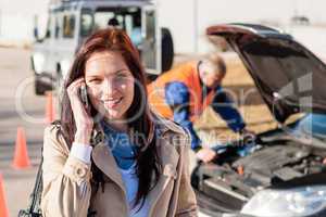 Woman talking on cellphone after car breakdown