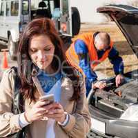 Woman dialing on cellphone after car breakdown