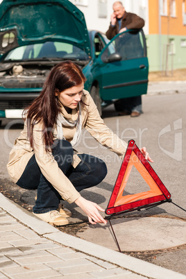 Woman putting triangle sign for car breakdown