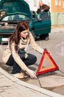 Woman putting triangle sign for car breakdown