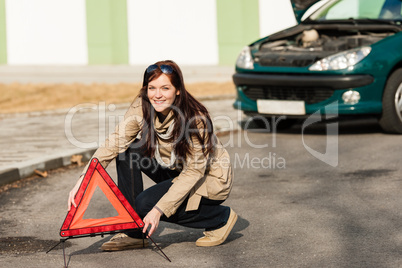 Woman putting warning triangle on the road