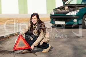 Woman putting warning triangle on the road