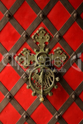 Rote Tür mit Beschlägen und verziertem Türklopfer