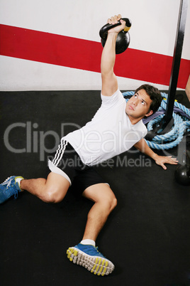 Young man doing kettlebell workout on gym