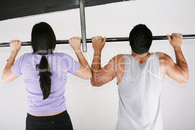 Young adult fitness woman and man preparing to do pull ups in pu