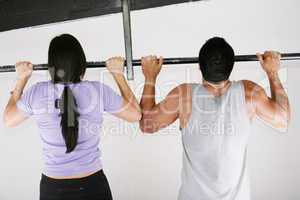 Young adult fitness woman and man preparing to do pull ups in pu