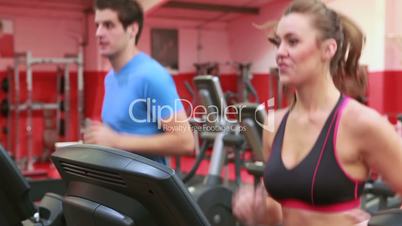 Woman and man jogging on treadmills