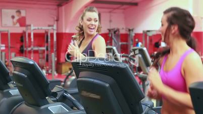 Two women talking while running on treadmill