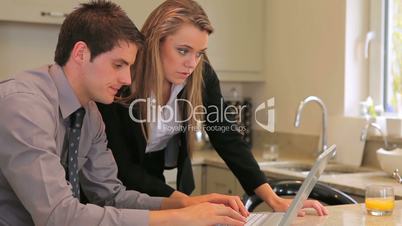 Couple sitting in the kitchen looking at laptop