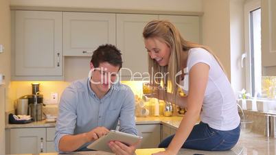 Man showing tablet pc to wife sitting on counter