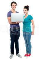 Teen friends holding laptop. Full length shot