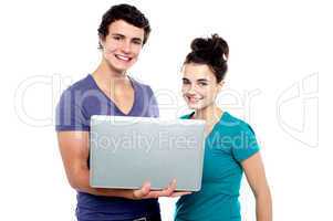 Charming teen couple holding a laptop