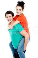 Happy young girl enjoying piggyback ride on her boyfriend back