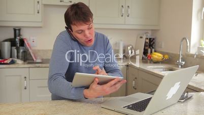 Man using laptop, mobile phone and two tablets busily