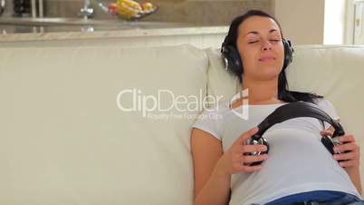 Woman listening to music with headphones on belly