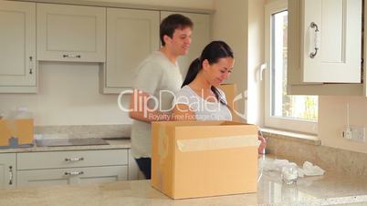 Woman packing moving box with man carrying boxes