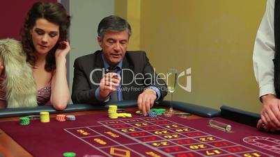 Woman and man placing bets on roulette table