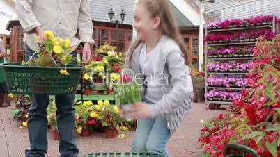 Little girl choosing plant and putting it in basket