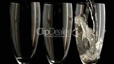 Three champagne flutes with one being filled