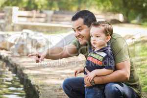 Hispanic Father Points with Mixed Race Son at the Park