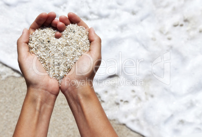 Mellow heart shaping female hands above beach