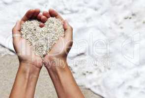 Mellow heart shaping female hands above beach
