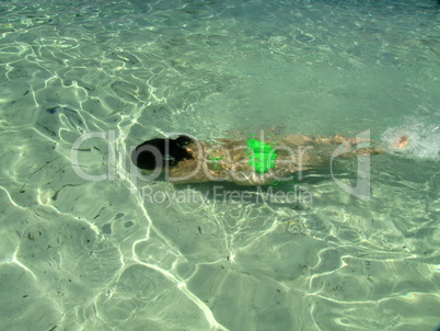 young girl plays games in shallow green water of Vahti beach, Thassos, Greece