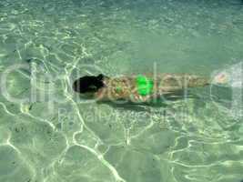 young girl plays games in shallow green water of Vahti beach, Thassos, Greece
