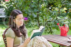 Junge Frau liest im Garten, young woman reading in a garden