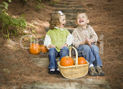 Brother and Sister Children Sitting on Wood Steps with Pumpkins