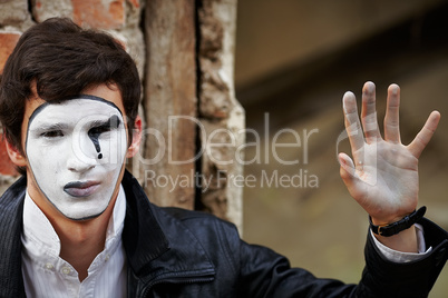 Guy mime against an old brick wall.