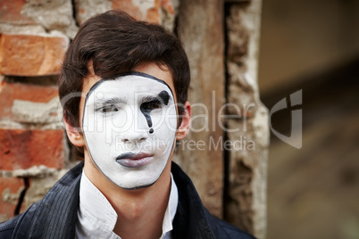 Guy mime against an old brick wall.