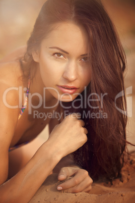 A beautiful girl in a bikini pours sand