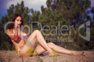 A beautiful girl in a bikini pours sand