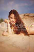 Beautiful girl in a bikini pours sand