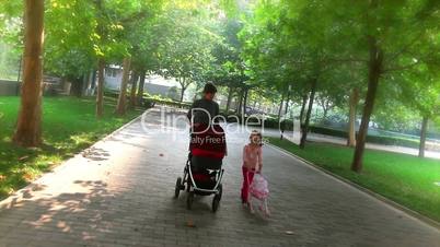 Mother and daughter pushing baby strollers in a park