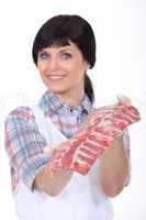 Female butcher stood with raw meat