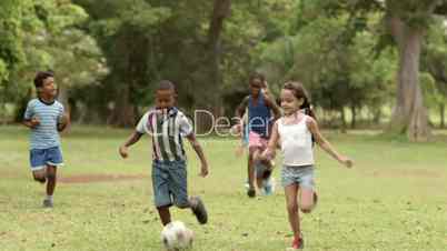 Happy children playing soccer with ball in park