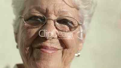 Old woman with eyeglasses smiling and looking at camera