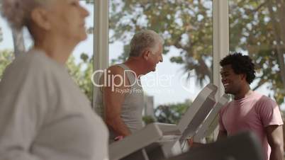 Trainer helping senior man exercising in wellness club