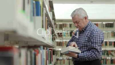 Happy old man reading and choosing book in library