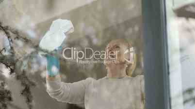 Senior woman cleaning window glass at home
