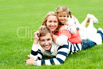 Smiling family of three piled on top of each other