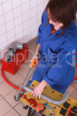 Female plumber sawing pipe