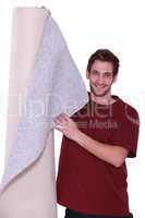 Young man standing with roll of carpet