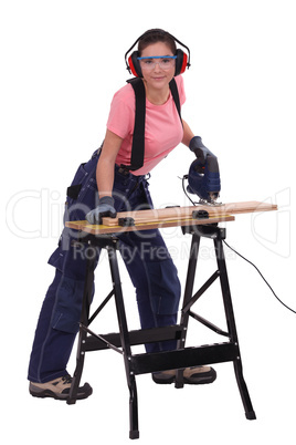 Woman cutting plank of wood with band saw