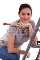 Woman with paint brush leaning on a ladder